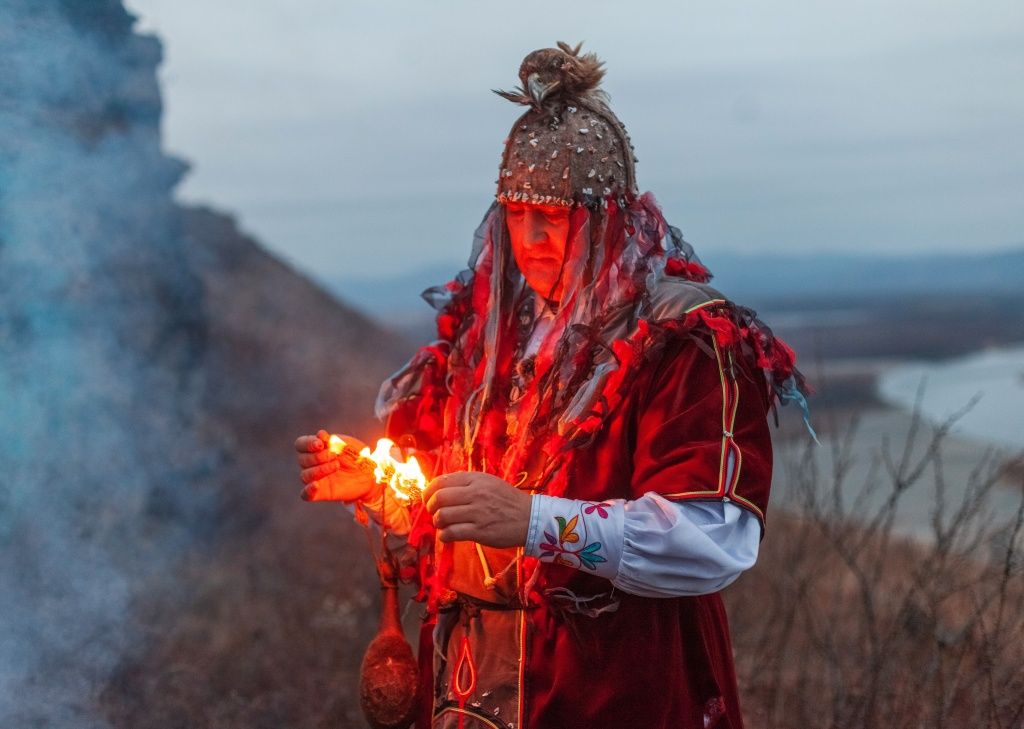 Фото Дениса Мукимова. Шаман из Хакасии окуривает местность можжевельником. В Хакасии этот невысокий кустарник называется арчын, в Тыве &mdash; артыш 